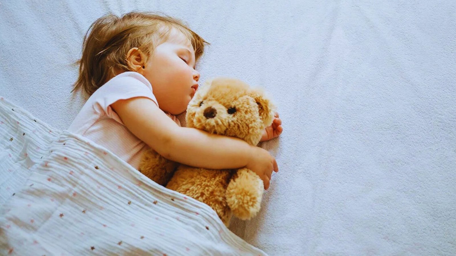 A little girl peacefully sleeping with a teddy bear, embodying comfort and tranquility.