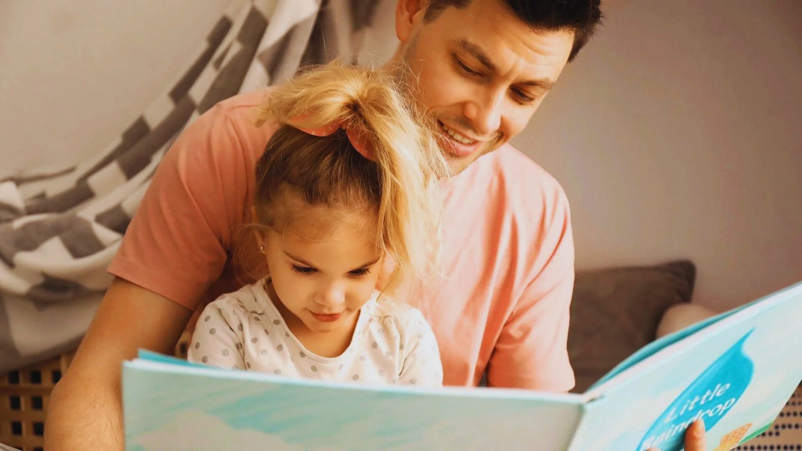 A man and a little girl sit together, reading a book, sharing a cozy moment before bedtime.