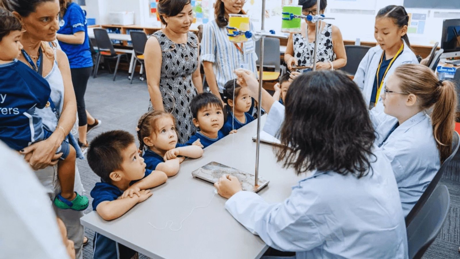 A teacher guides a diverse group of children engaged in learning activities in a bright classroom setting.