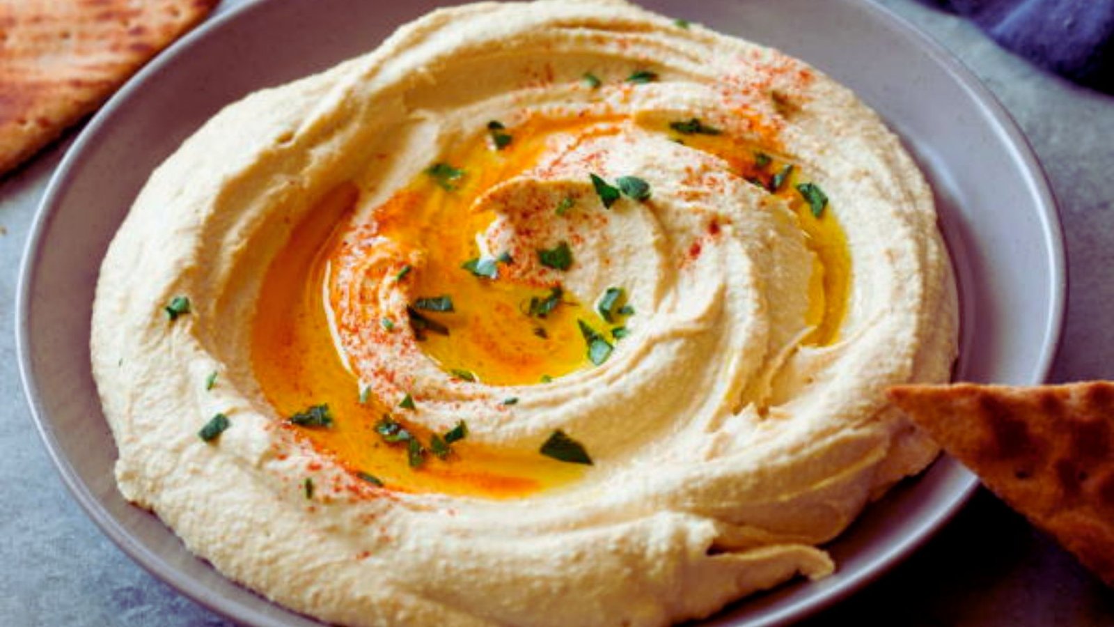 Creamy hummus served with warm pita bread on a wooden platter.