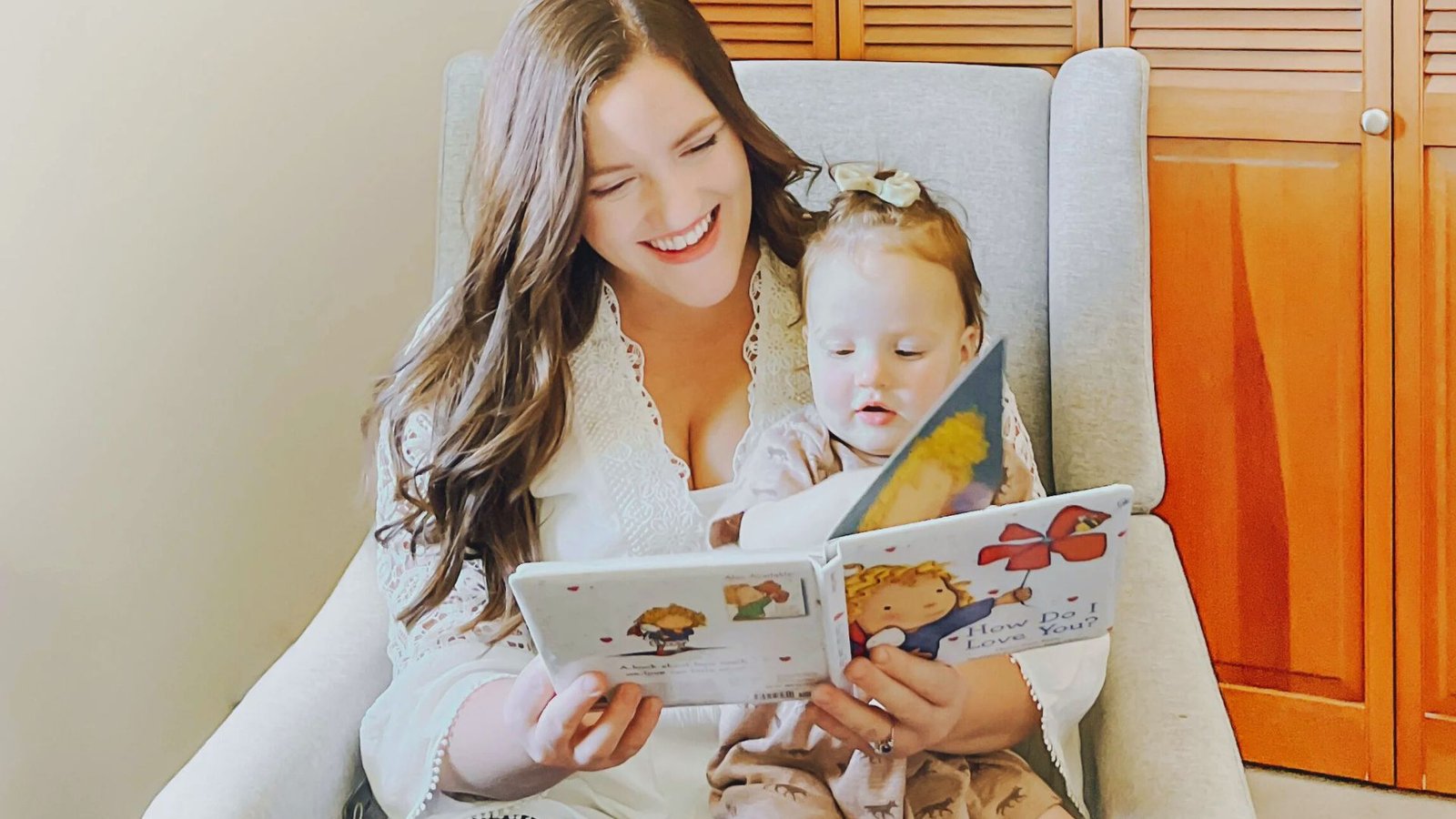 A woman reads to her b aby in a chair, illustrating the importance of bonding during the 2 to 1 nap transition.