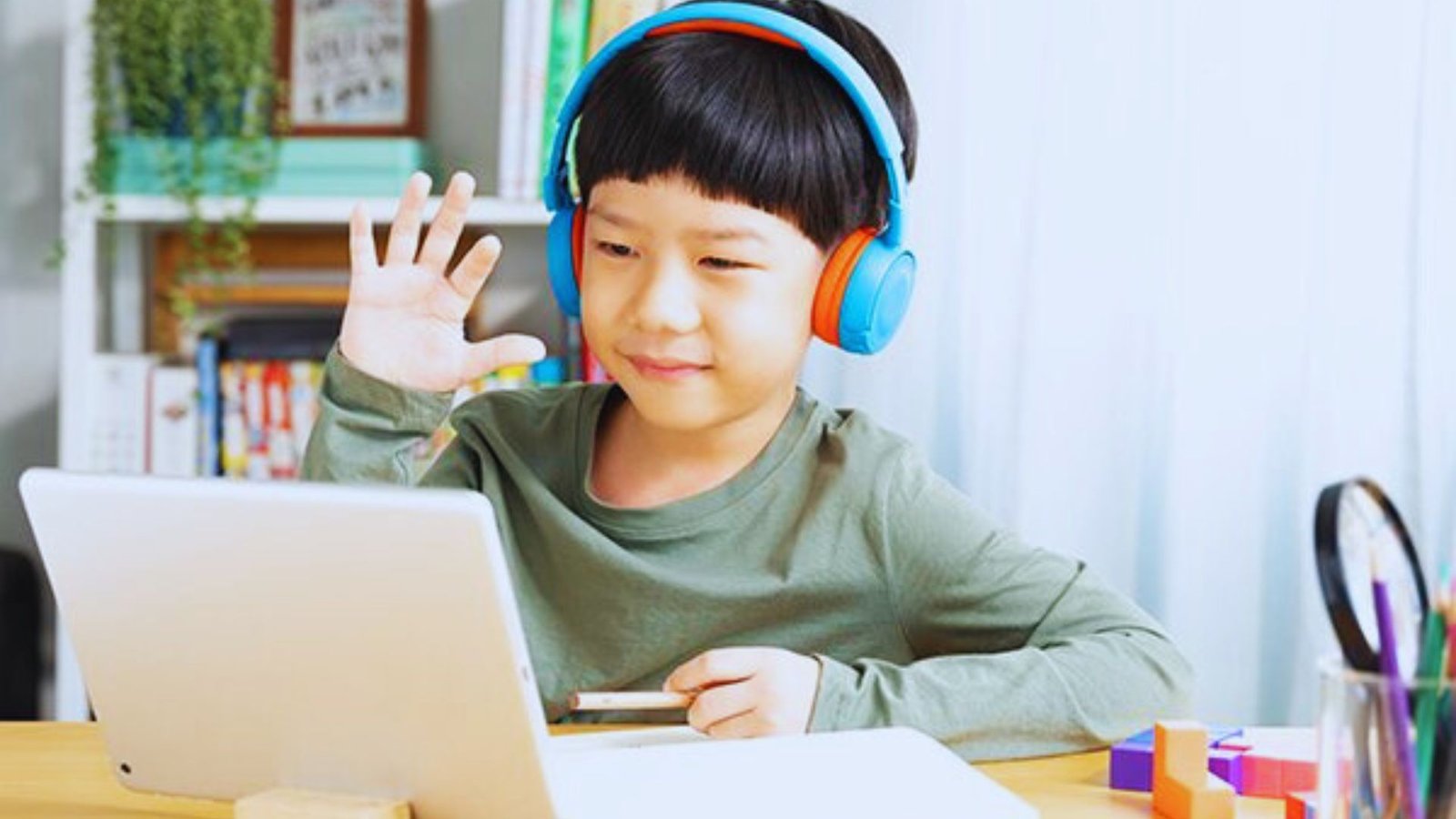 A young boy with headphones is focused on a laptop, representing trends in early childhood education.