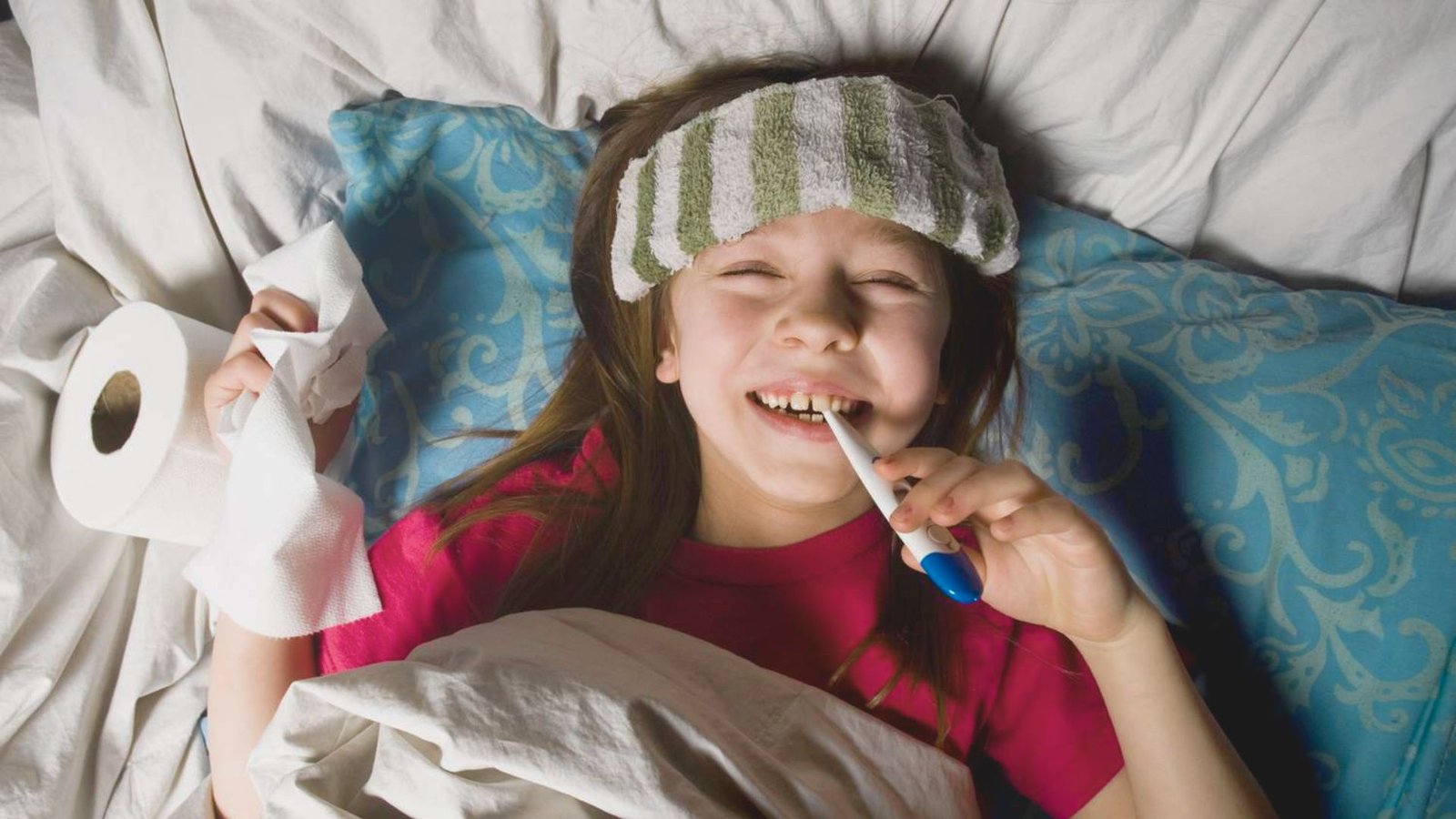 A young girl with a headband holds a thermometer while lying in bed, ready for her nighttime routine.