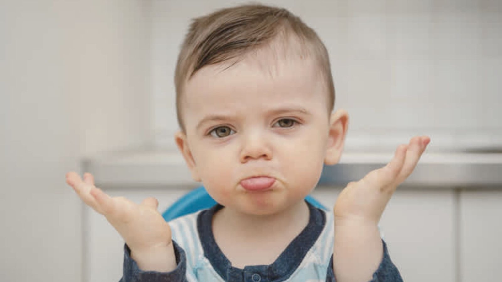 A young boy with his hands raised, displaying a puzzled expression as if asking "why."