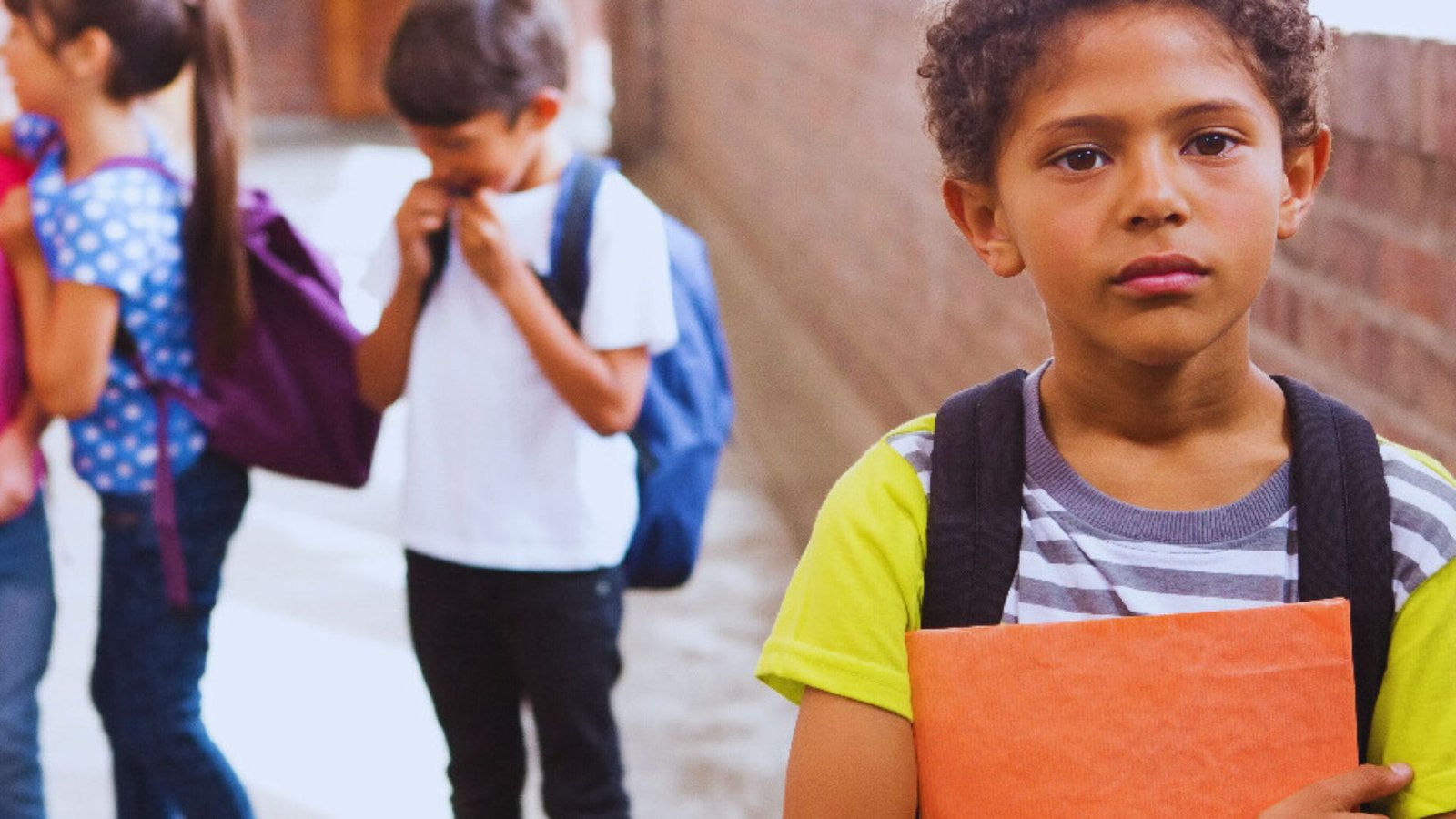 A young boy stands confidently in front of a group of children, engaging them with a smile.