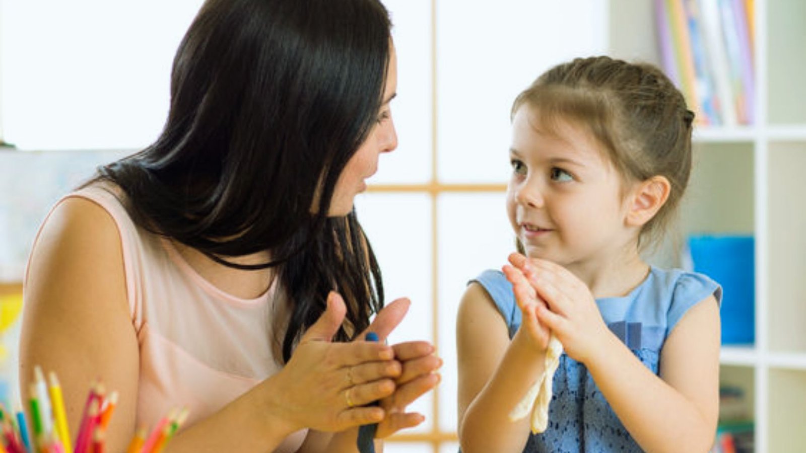 A woman and a young girl sit together at a table, engaged in conversation and sharing a moment