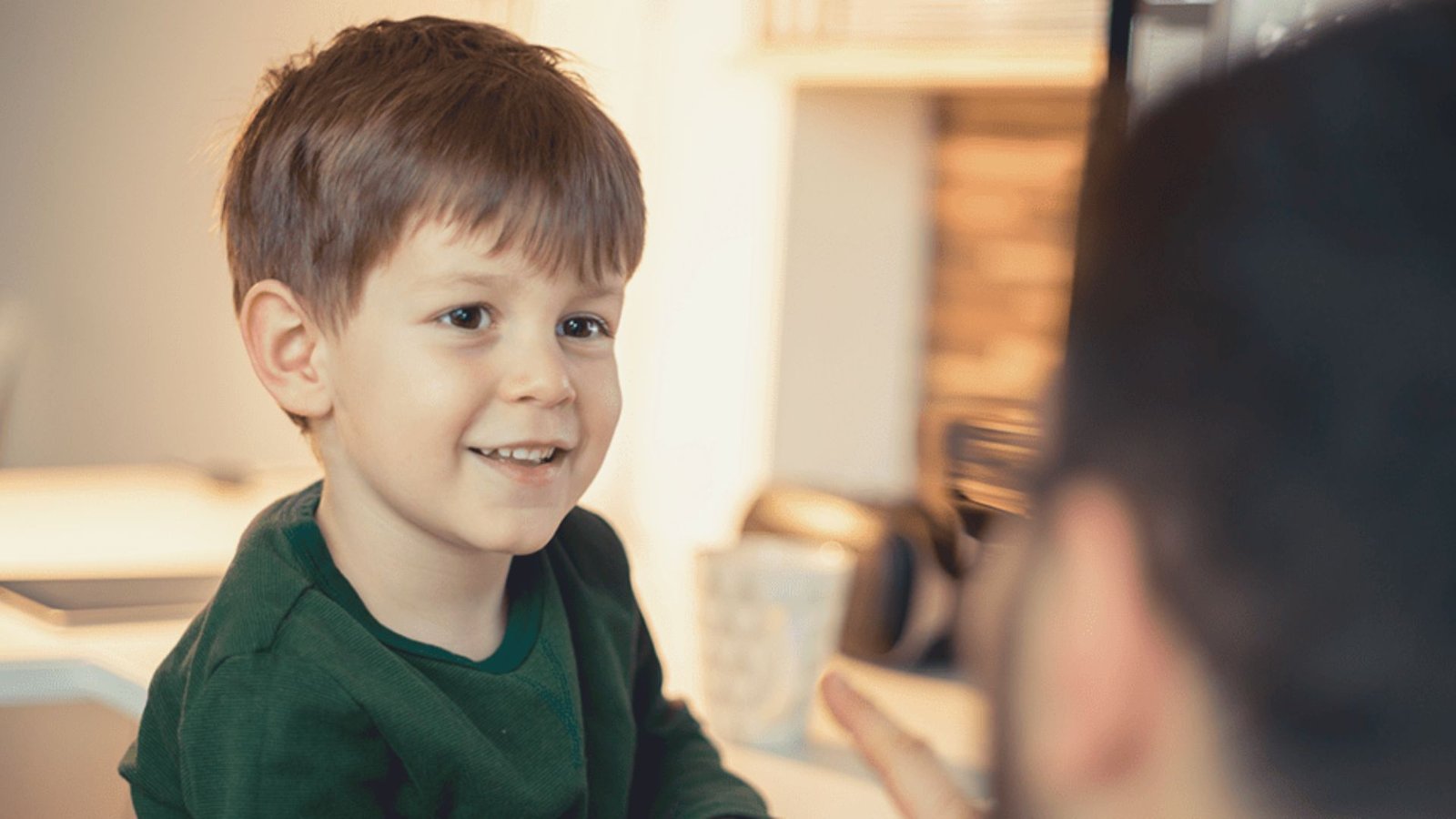 A smiling young boy is seated, radiating joy and curiosity