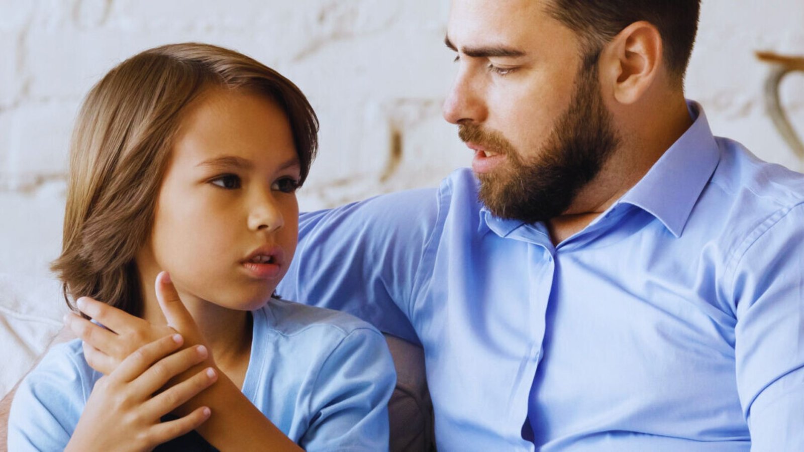 A man and a young boy are sitting together on a couch, sharing a moment of relaxation and companionship.