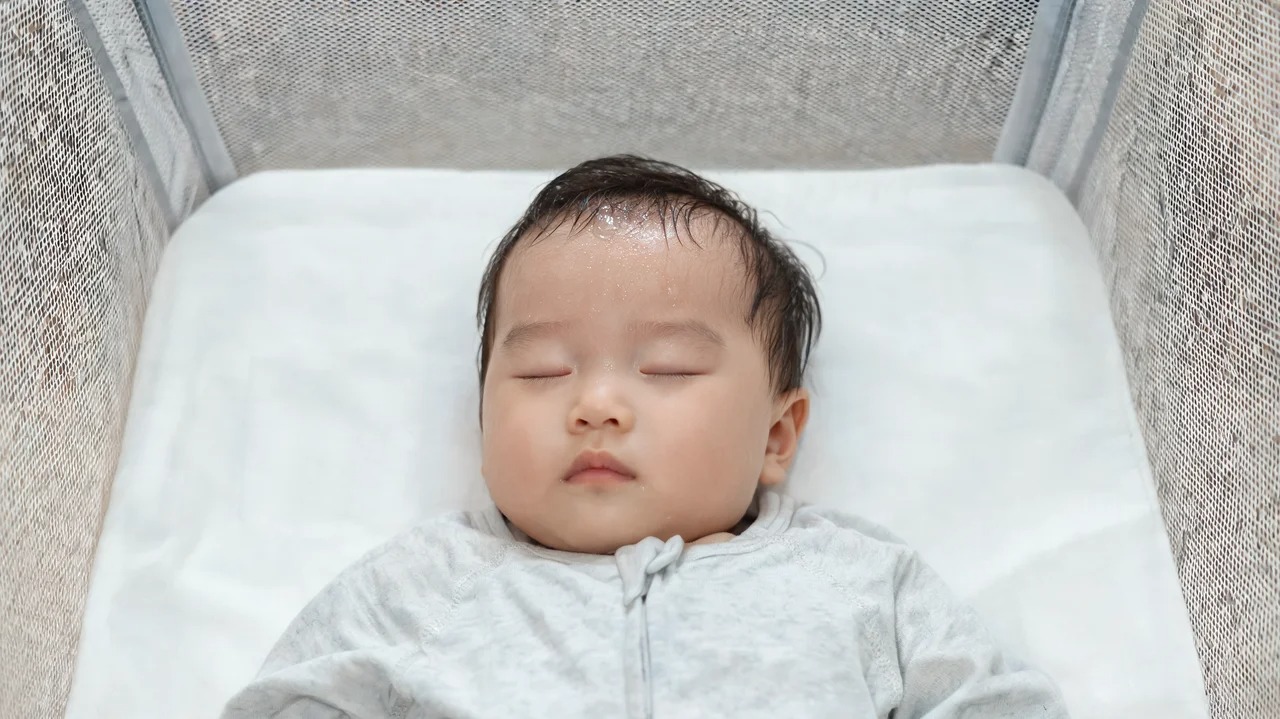 Baby sleeping on their back in a bare crib, wearing a wearable blanket and no hat 
