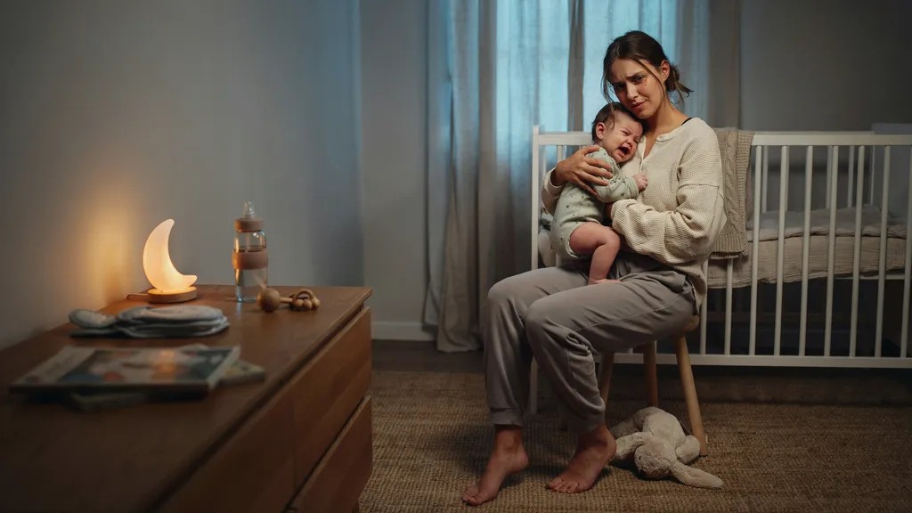 Parent comforting a baby during a sleep regression stage in a cozy nursery.