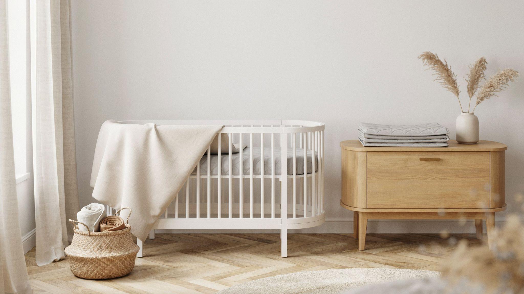 Bassinet with waterproof mattress protector, fitted sheet, folded spare protector, clean organized modern nursery setup.