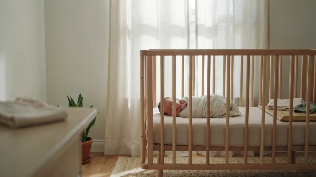 afe newborn sleep setup with crib, mattress, swaddle, and baby sleeping comfortably.