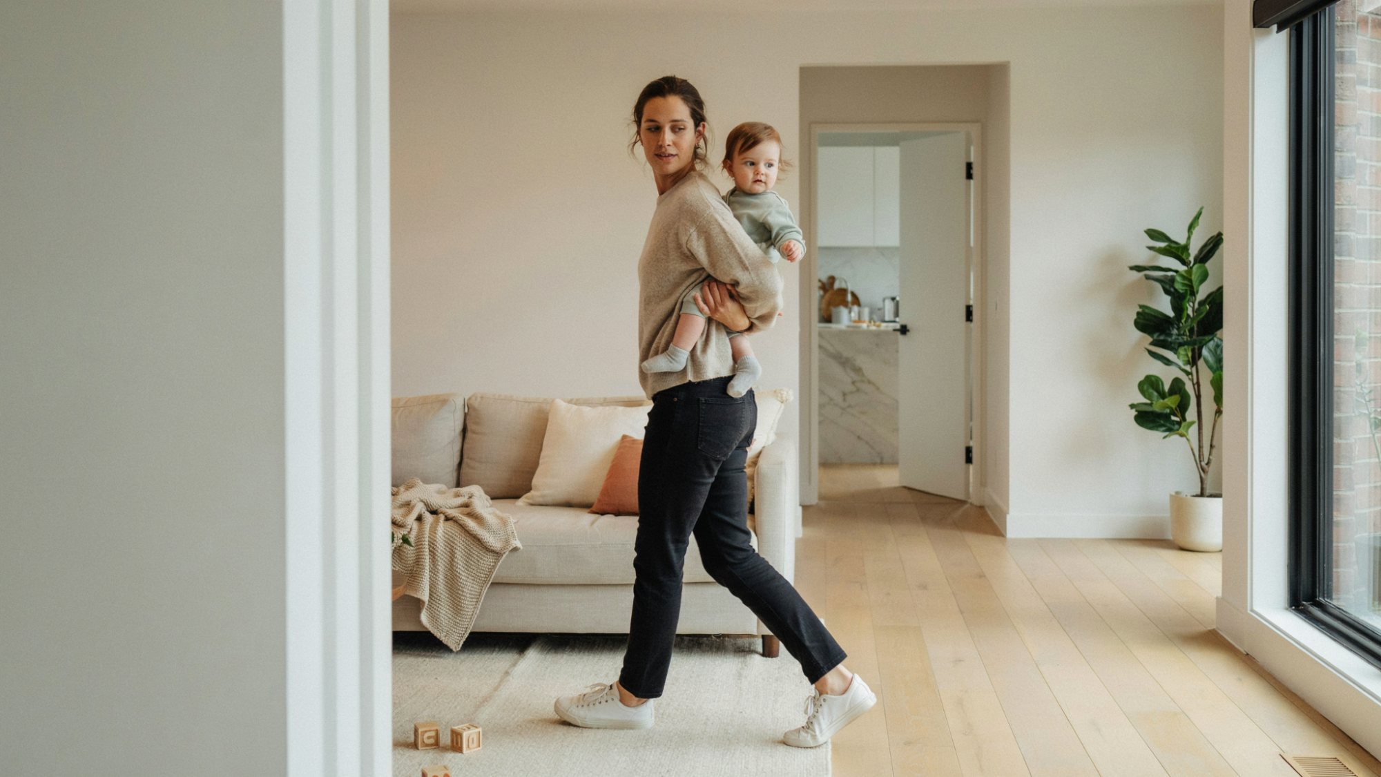 Parent carrying an older baby in a hip hold position while walking.