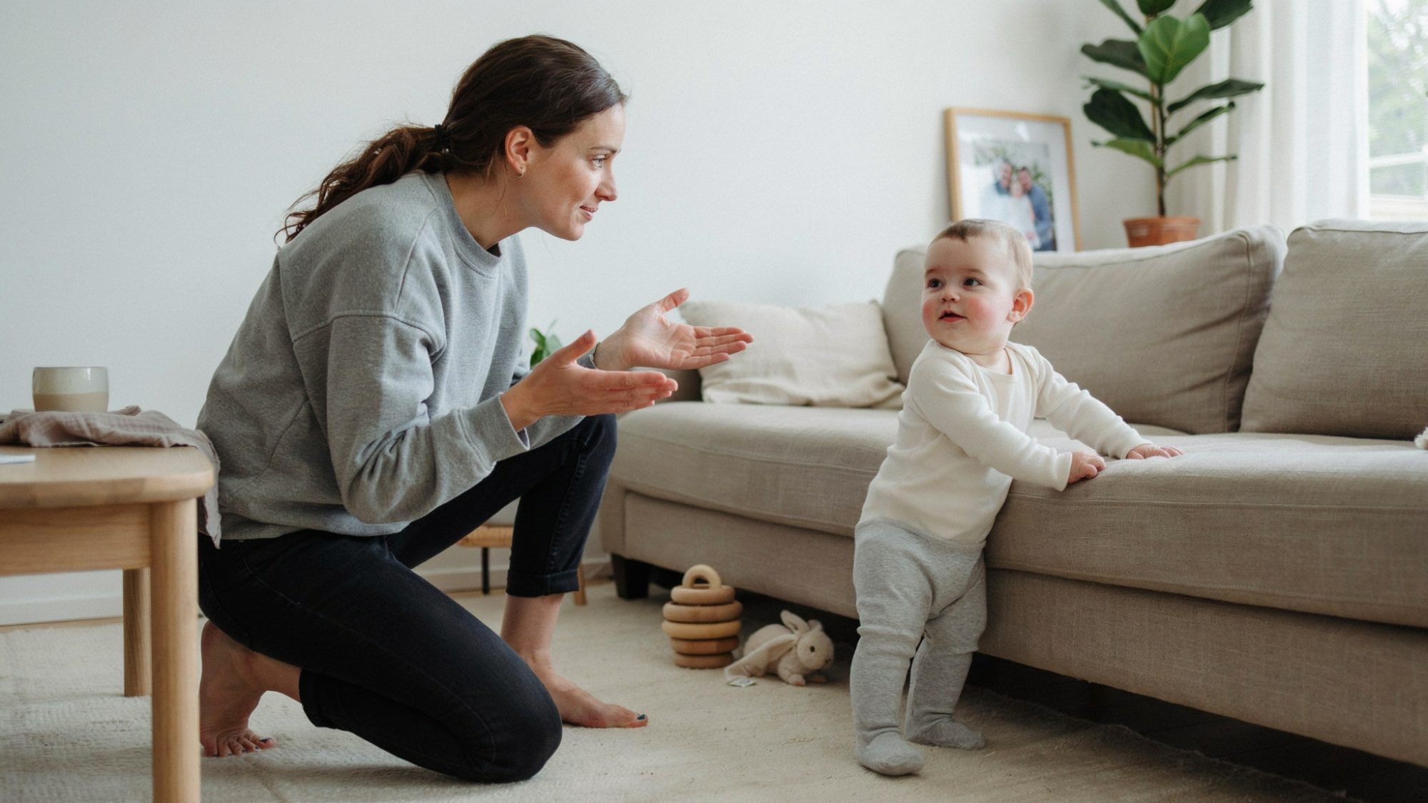 Parent encouraging a baby practicing standing later than peers, highlighting normal developmental differences and healthy growth with patience and reassurance.