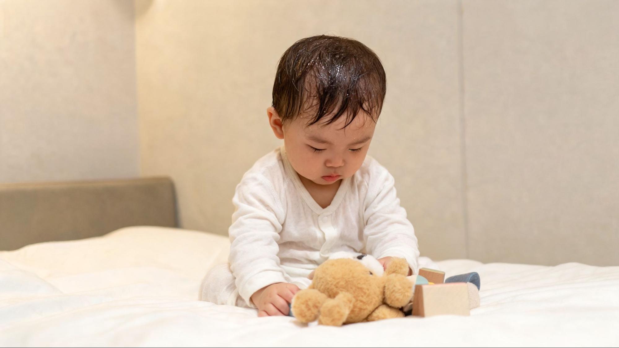 Baby with noticeable sweat on the head and damp clothing 