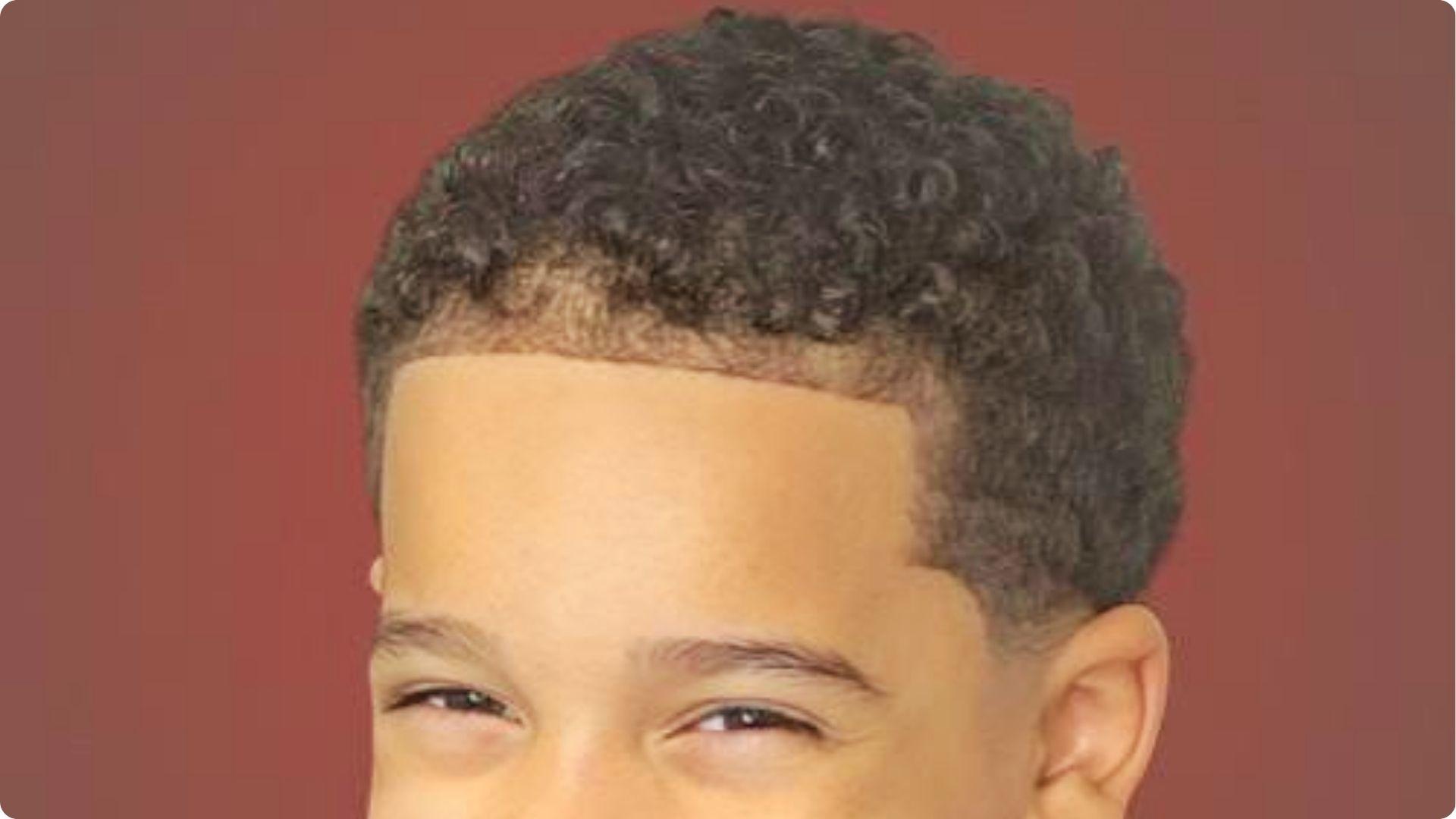 Smiling toddler with curly high top and low skin fade, defined ringlets, cute modern baby boy cut.