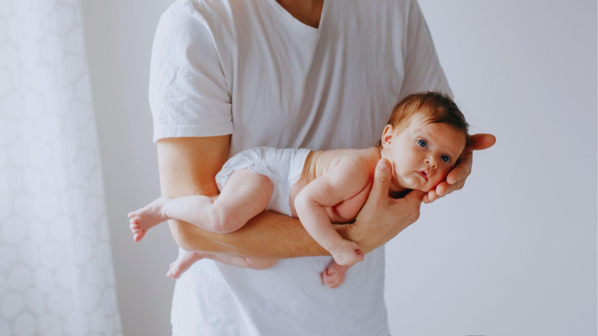 Parent soothing baby using gentle belly hold position.