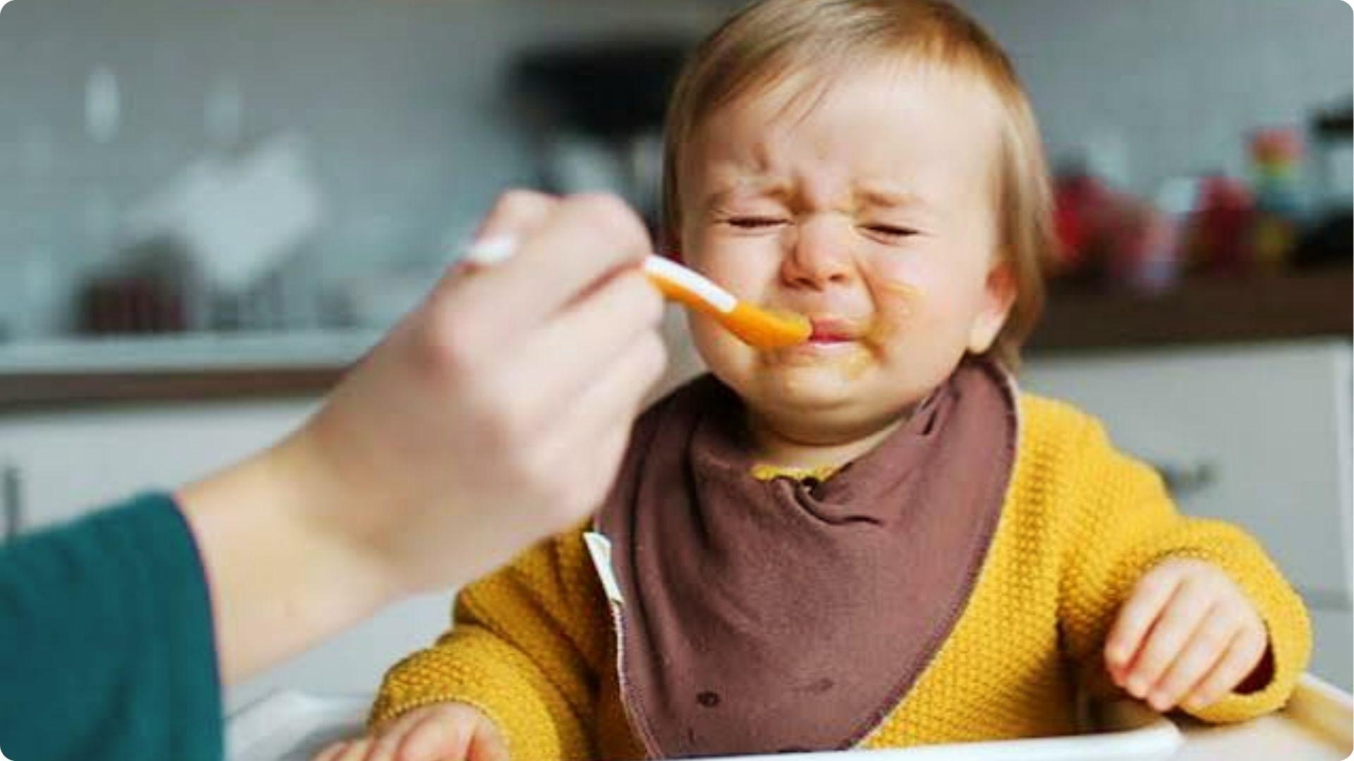 Baby cries with mouth open at mealtime, showing tantrums in eating because of distress breathing.