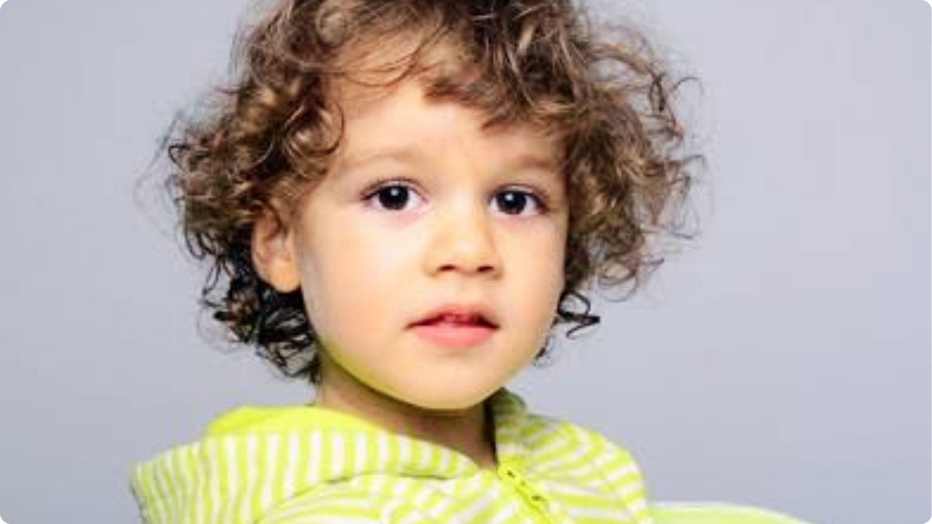 Back view of blonde curly high top with skin fade, tight ringlets on top, trendy baby boy haircut.