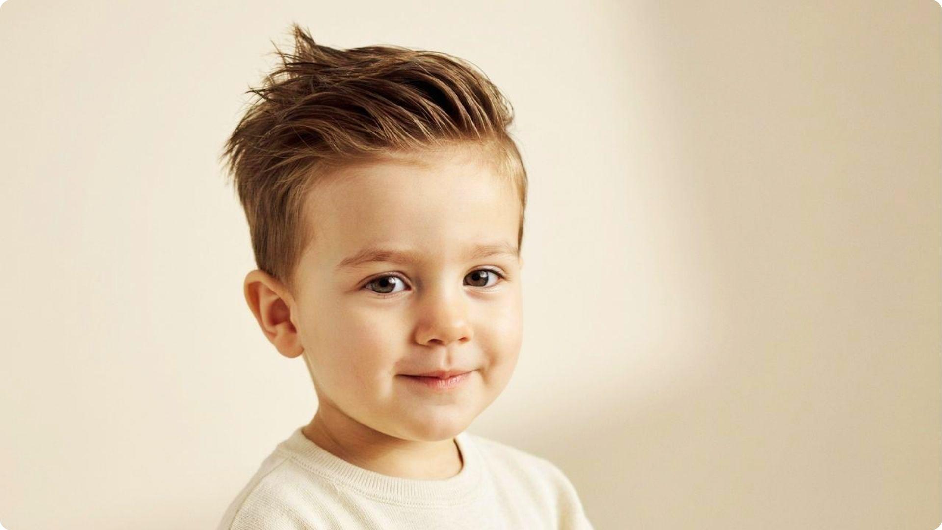 Toddler with textured spiky quiff and low taper fade, brushed-up messy top, cute modern baby boy cut.