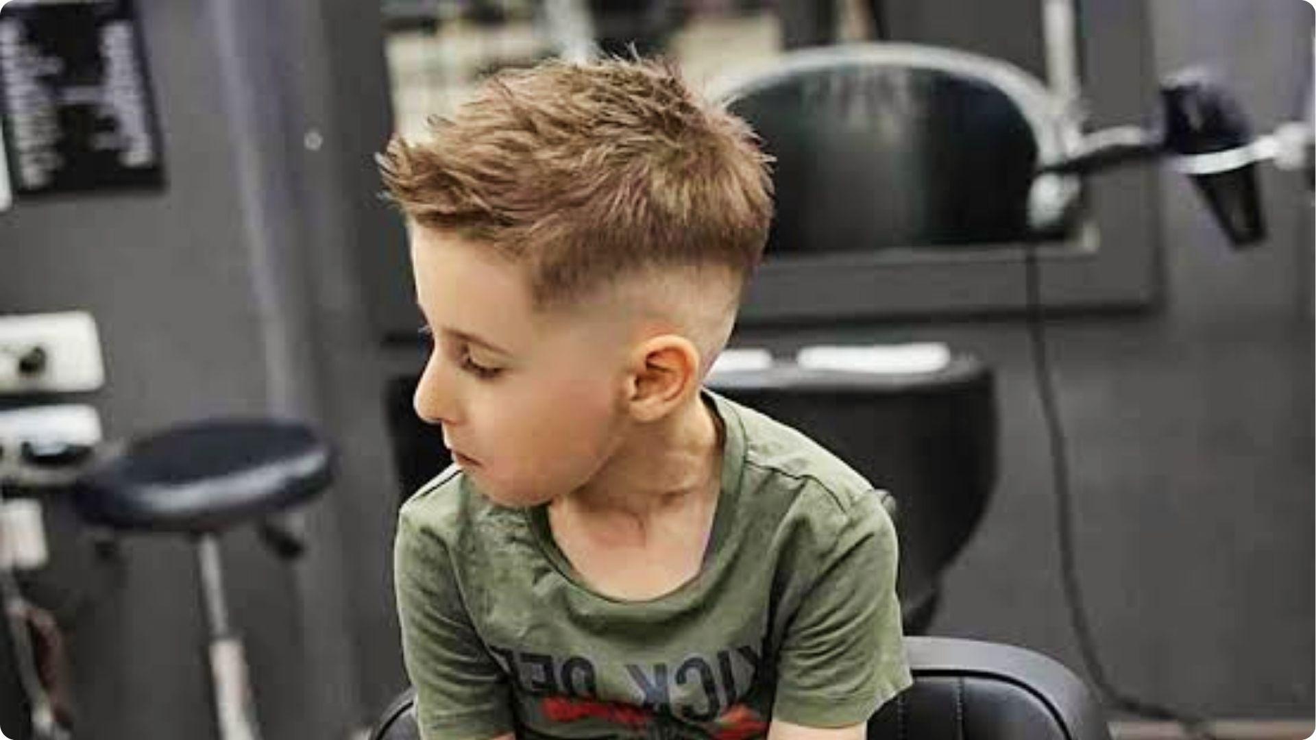 Toddler in barber shop with short spiky textured crop and low skin fade, modern baby boy haircut