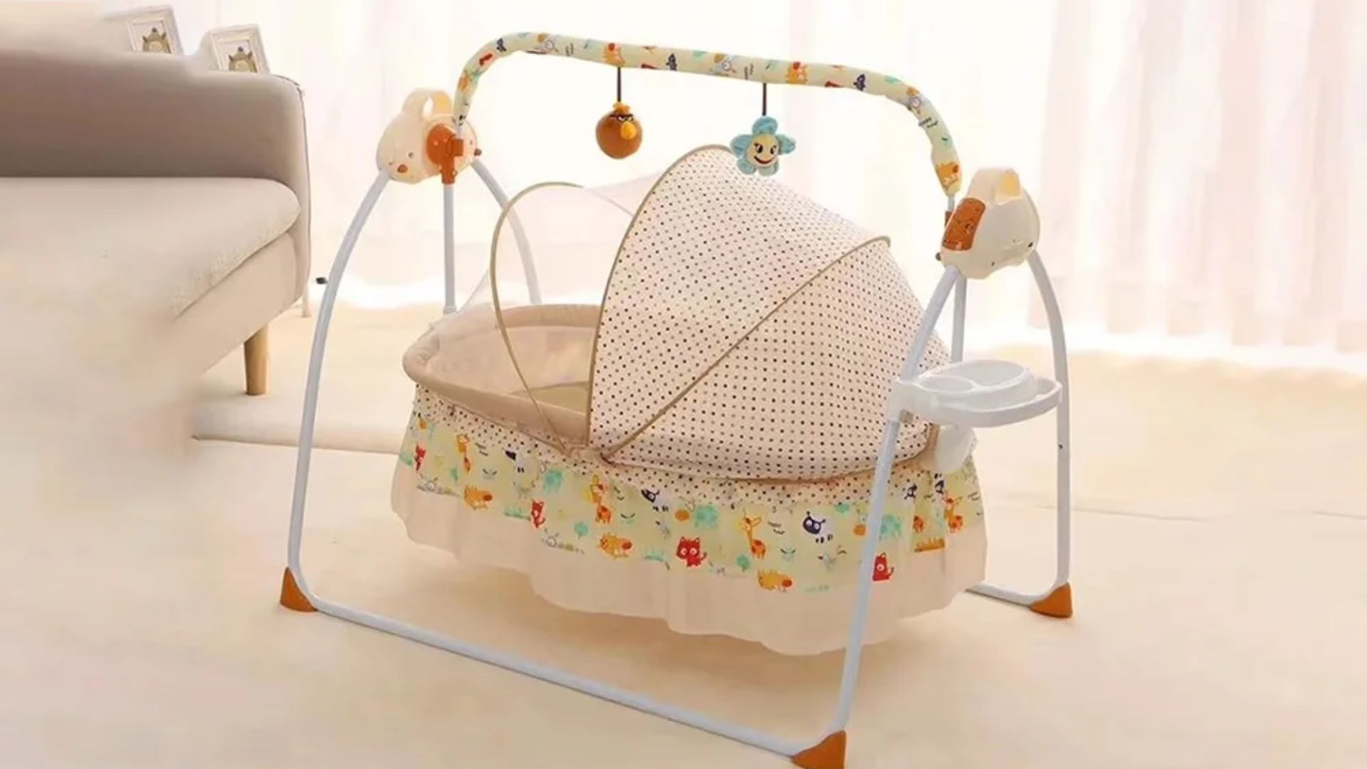 Baby electric bassinet swing with polka-dot canopy and colorful animal print, hanging flower and bird toys, in a bright living room.