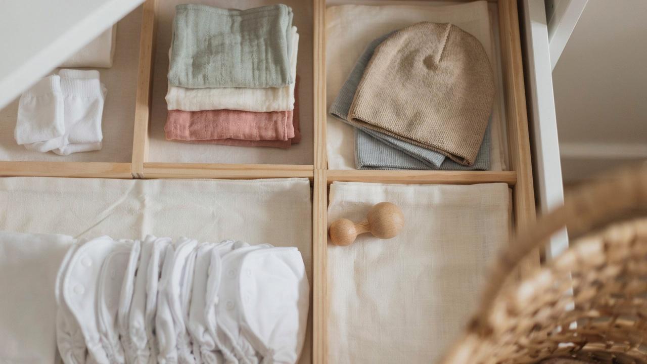 Baby socks, bibs, hats, and cloth diapers neatly organized in drawer dividers.