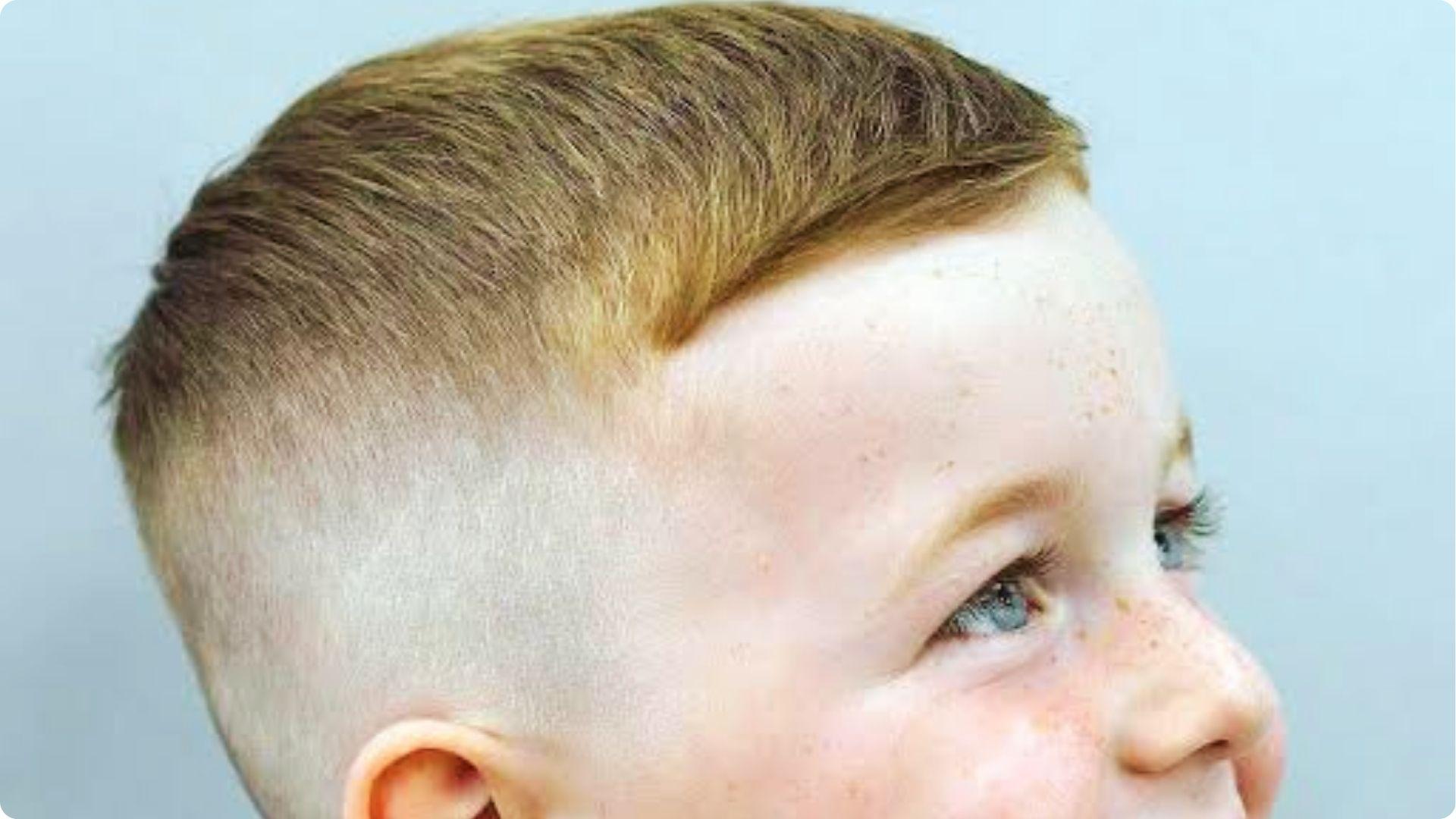 Toddler with sharp high skin fade and combed top, side view showing trendy modern baby boy haircut.