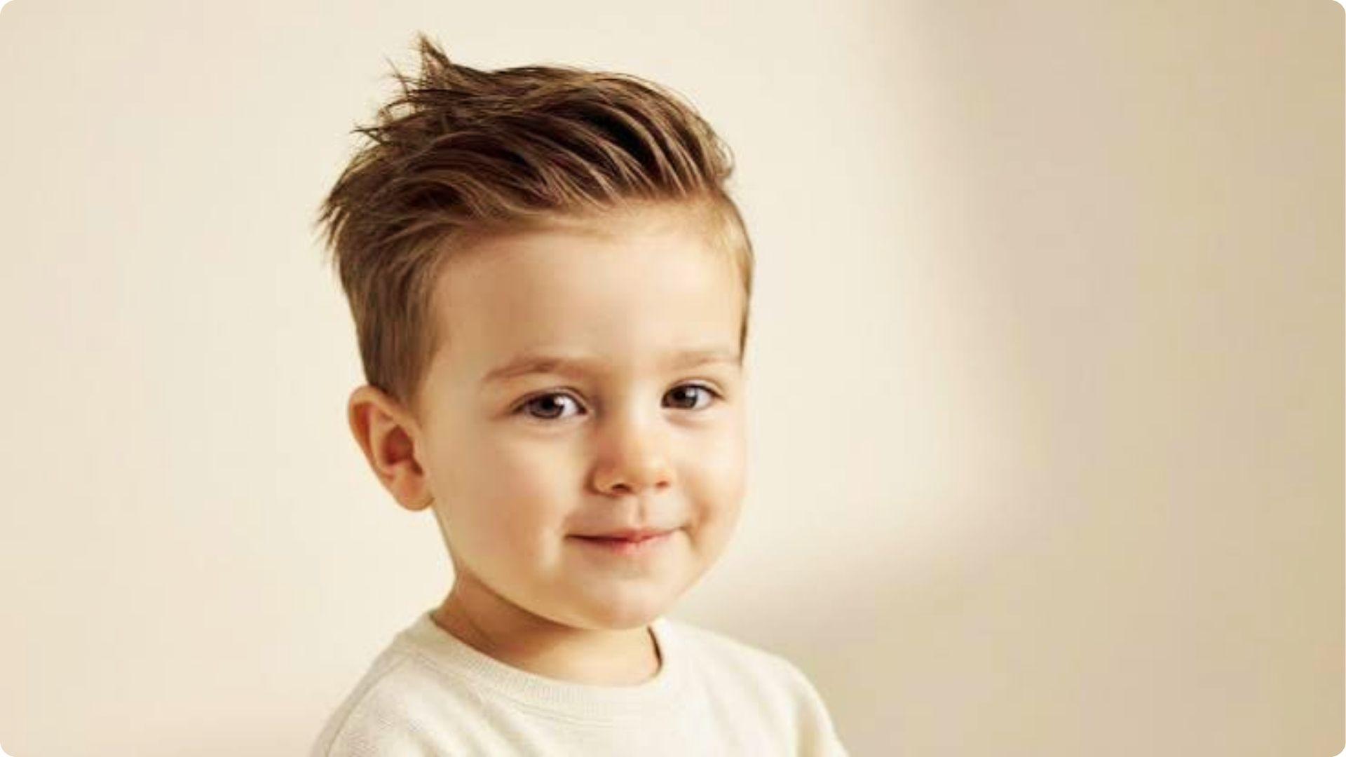 Stylish toddler with textured quiff and short faded sides, cream sweater, modern cute boy haircut.