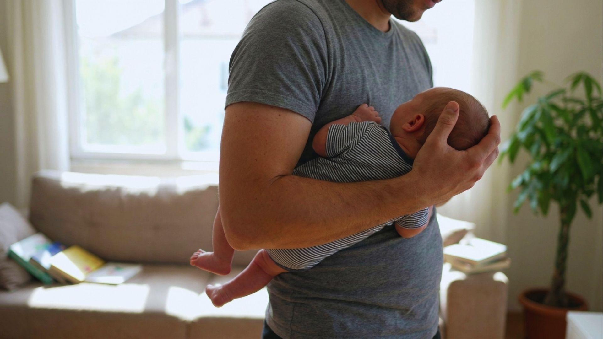 Parent using football hold with proper newborn head support.