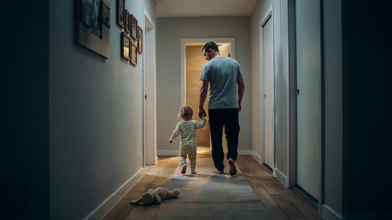 A toddler and a parent walking to the washroom at night.