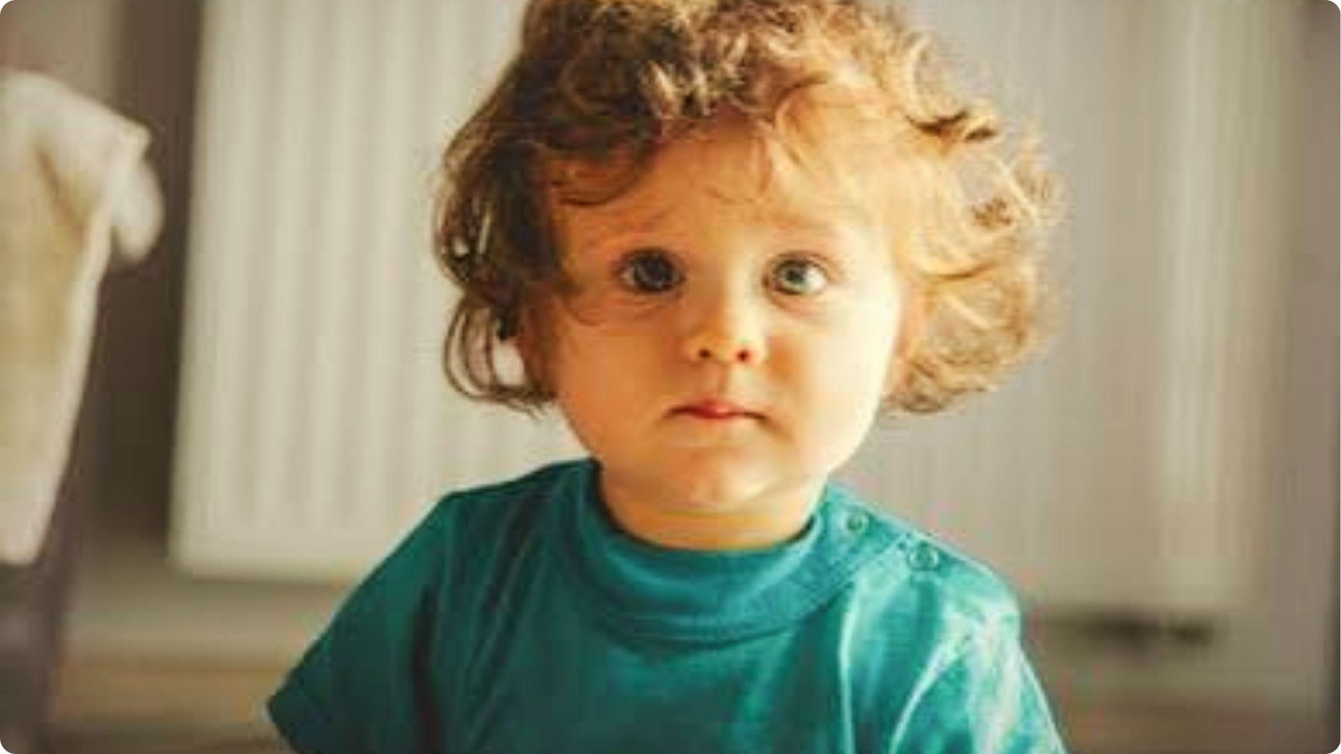 Toddler with soft curly bob and natural ringlets, loose curls framing face, natural baby boy haircut.