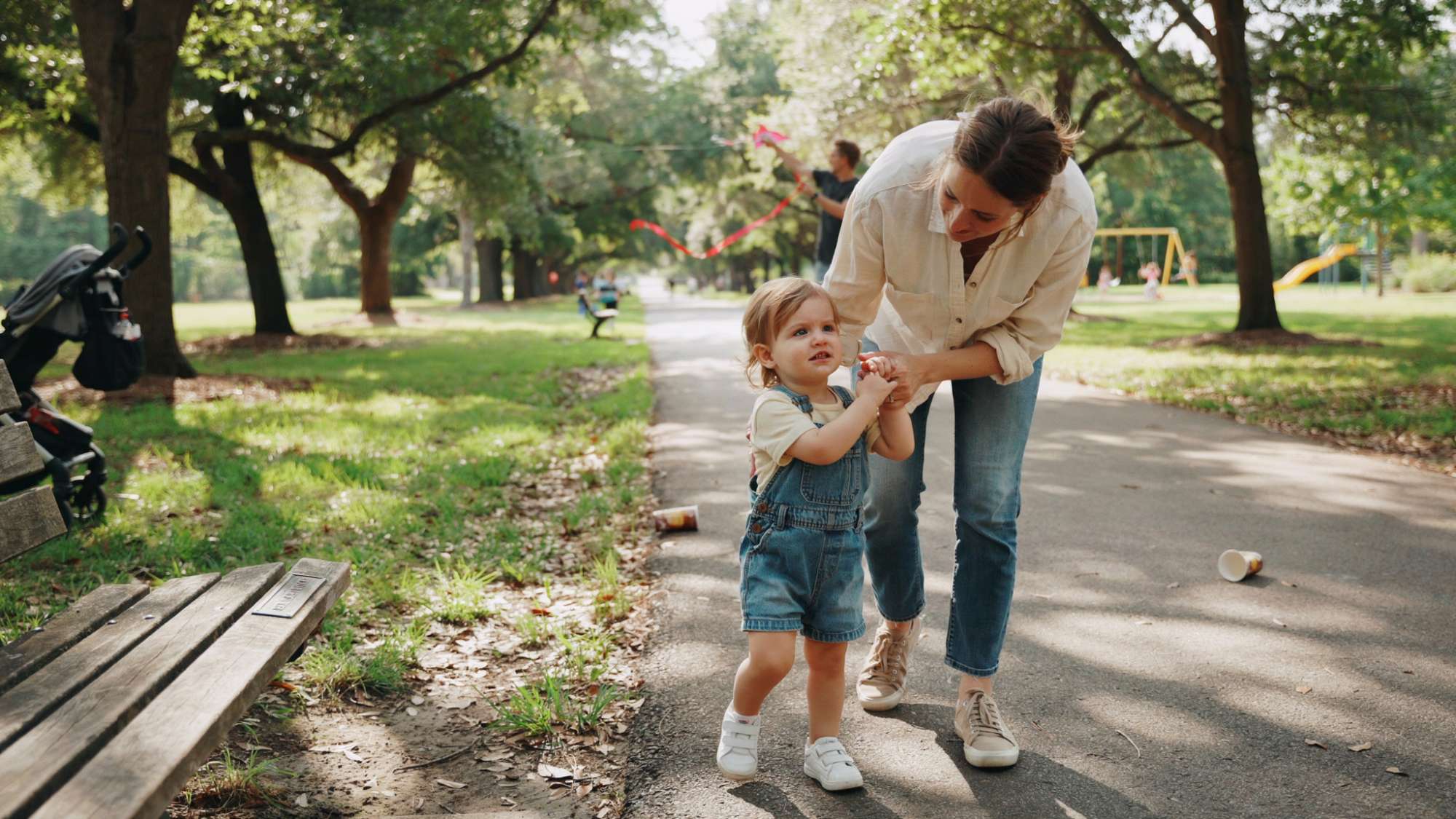 Toddler holding a parent's hand for comfort at the park.