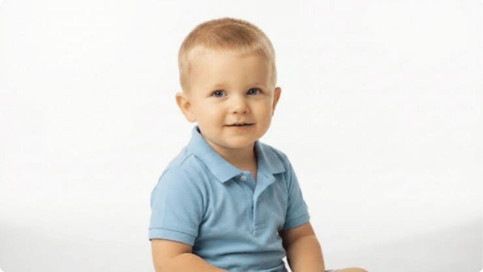 Toddler in light blue polo with short blonde buzz cut, clean minimal look, easy baby boy haircut.