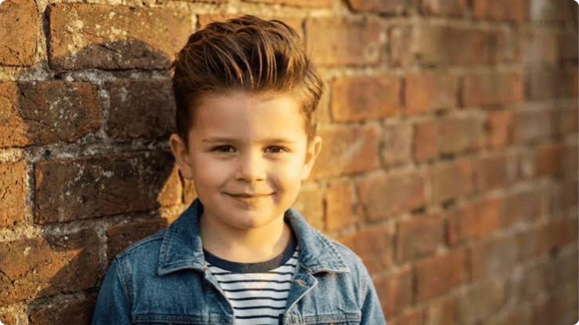 Toddler with spiky Thick Hair With Side Sweep and high skin fade in denim jacket cool modern look.
