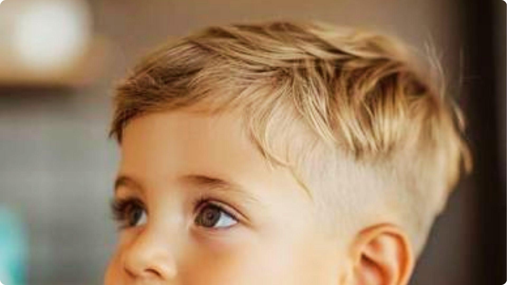 Toddler with textured side-swept fringe and low skin fade, soft layered top, modern baby boy haircut.