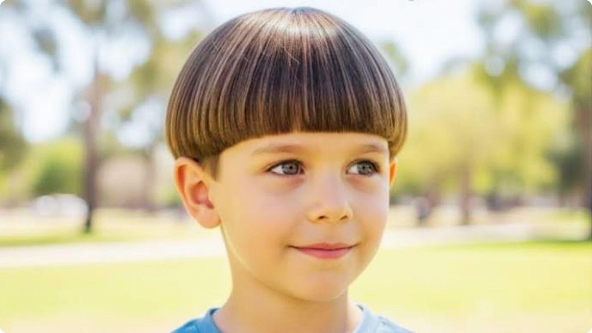 Toddler outdoors with neat straight bowl cut and blunt bangs, round shape, adorable baby boy haircut.