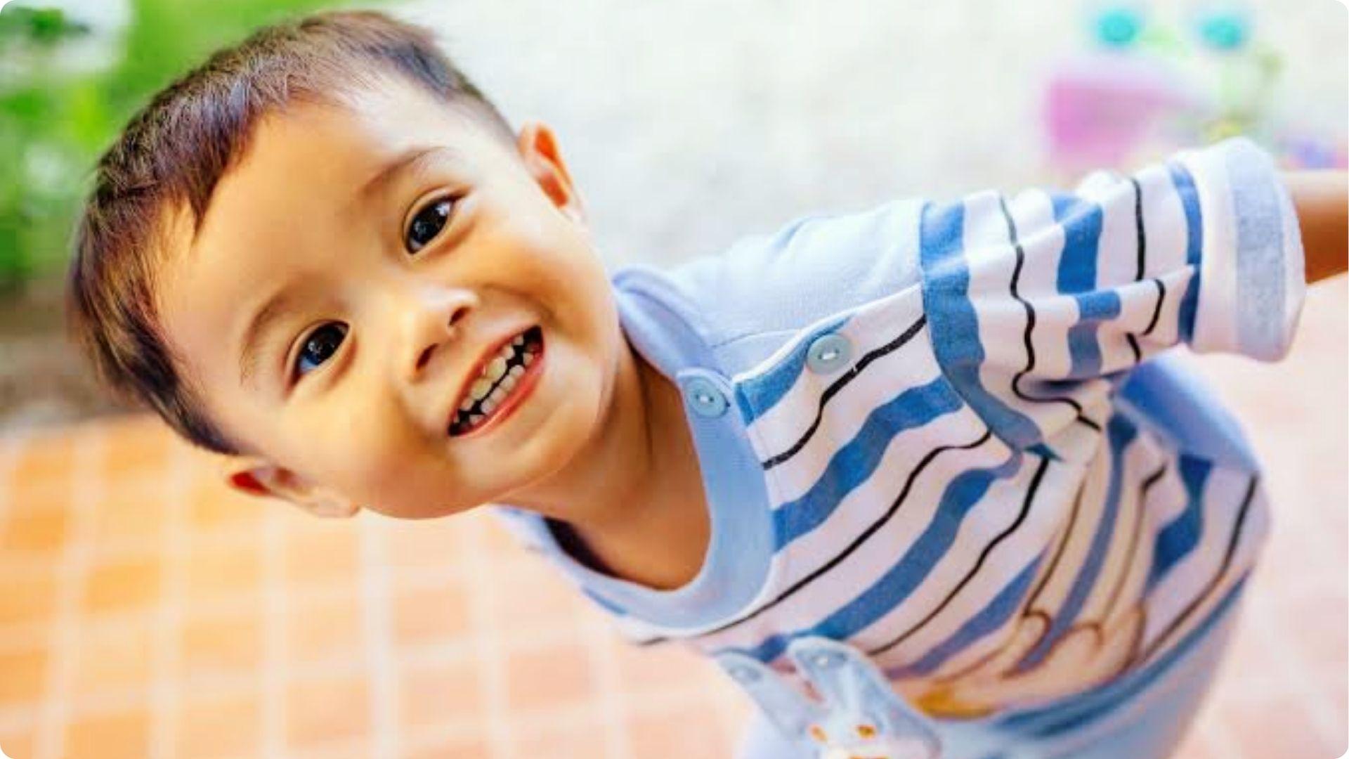 Smiling toddler with short cute buzz cut in blue striped shirt, playful easy summer baby boy haircut.