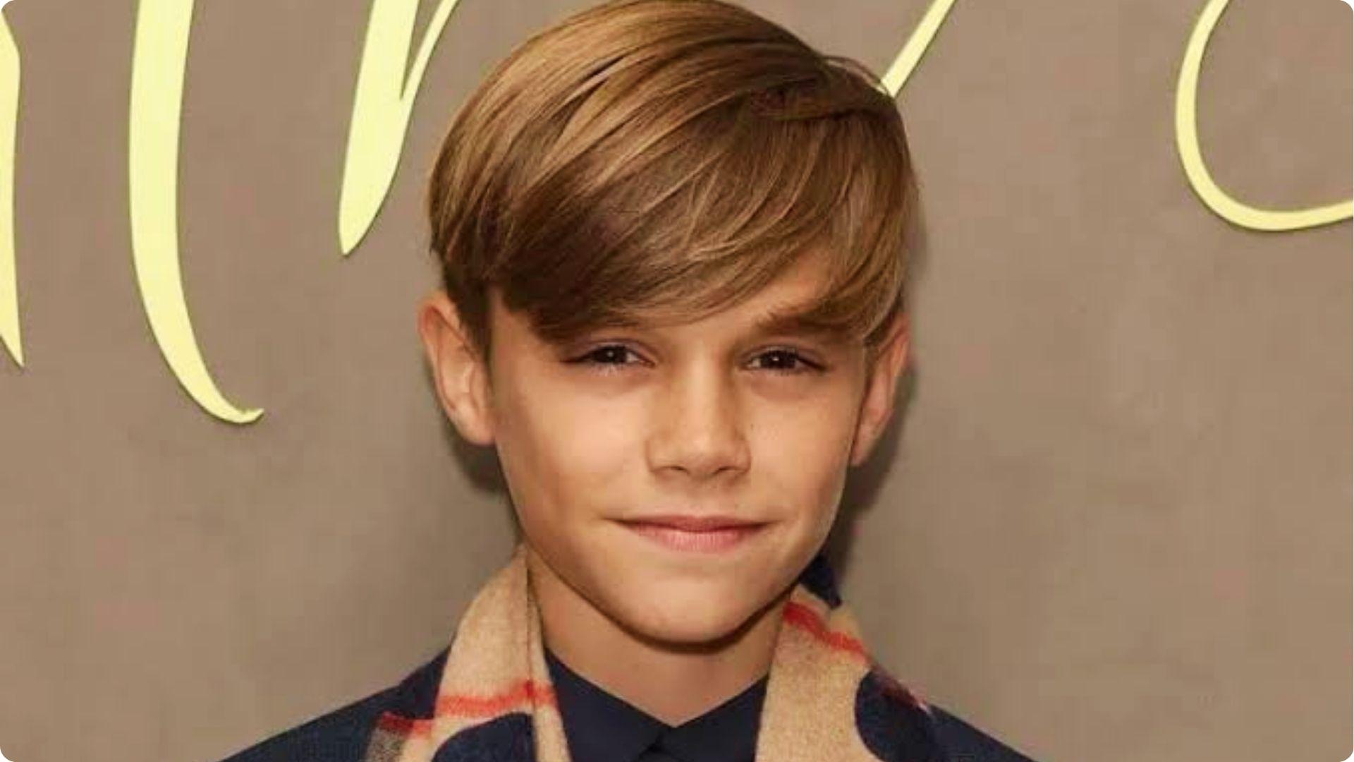 Boy with side-swept long layered hair covering forehead, smooth straight style, neat classic haircut.