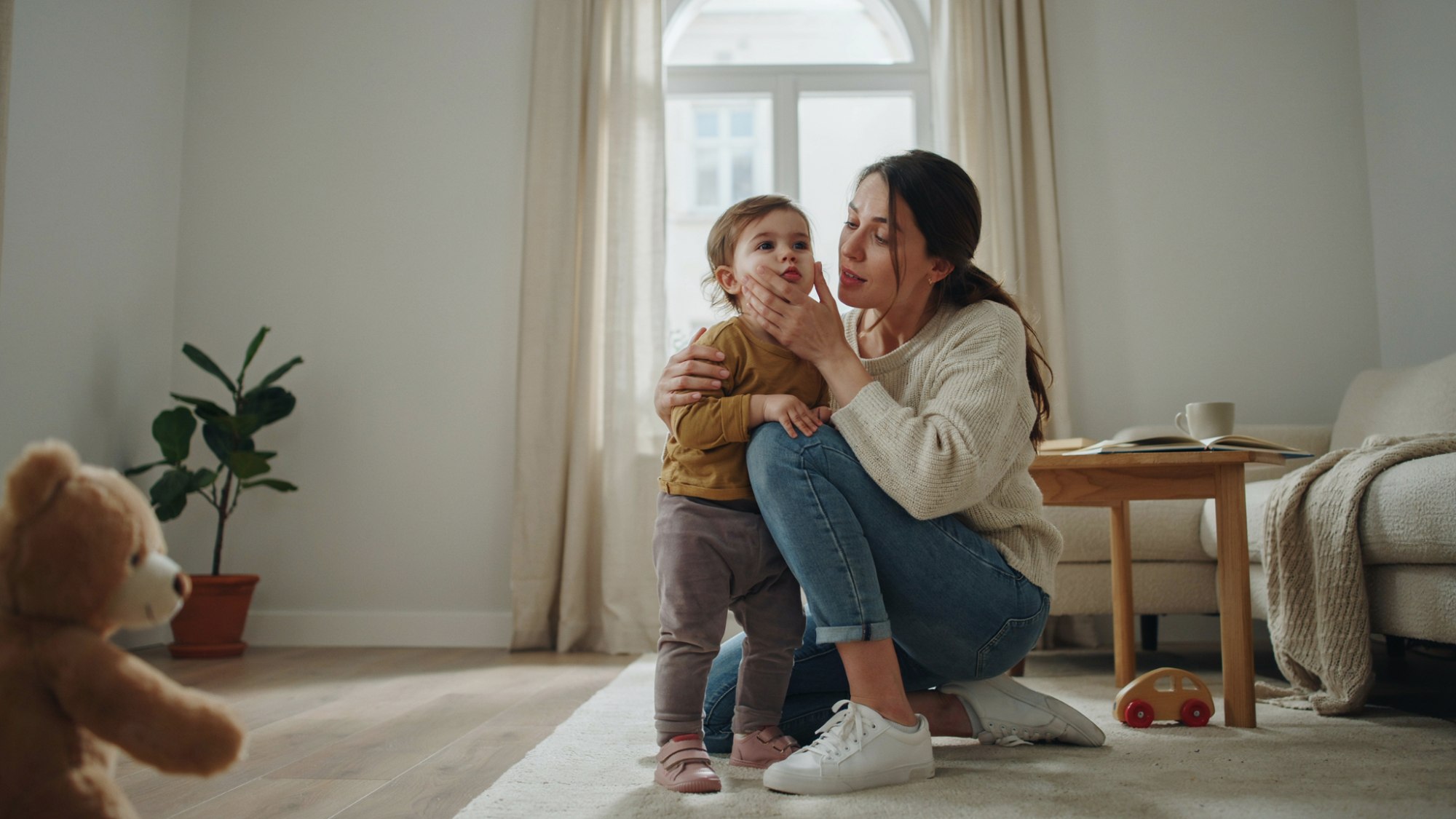 Parent comforting a clingy toddler at home.