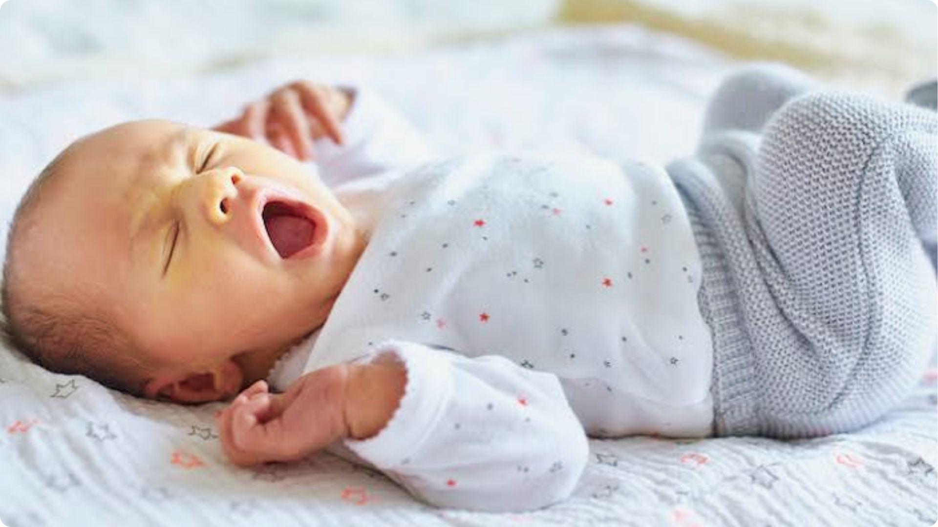 Yawning newborn struggling to fall asleep showing common overtired signs of sleep regression