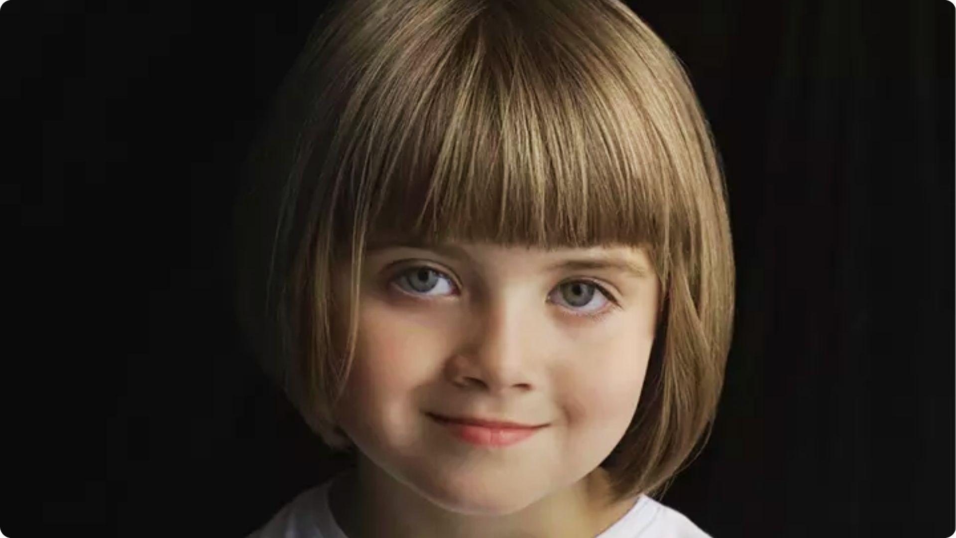 Child with straight blonde bob and full blunt bangs, chin-length smooth cut, cute toddler haircut style