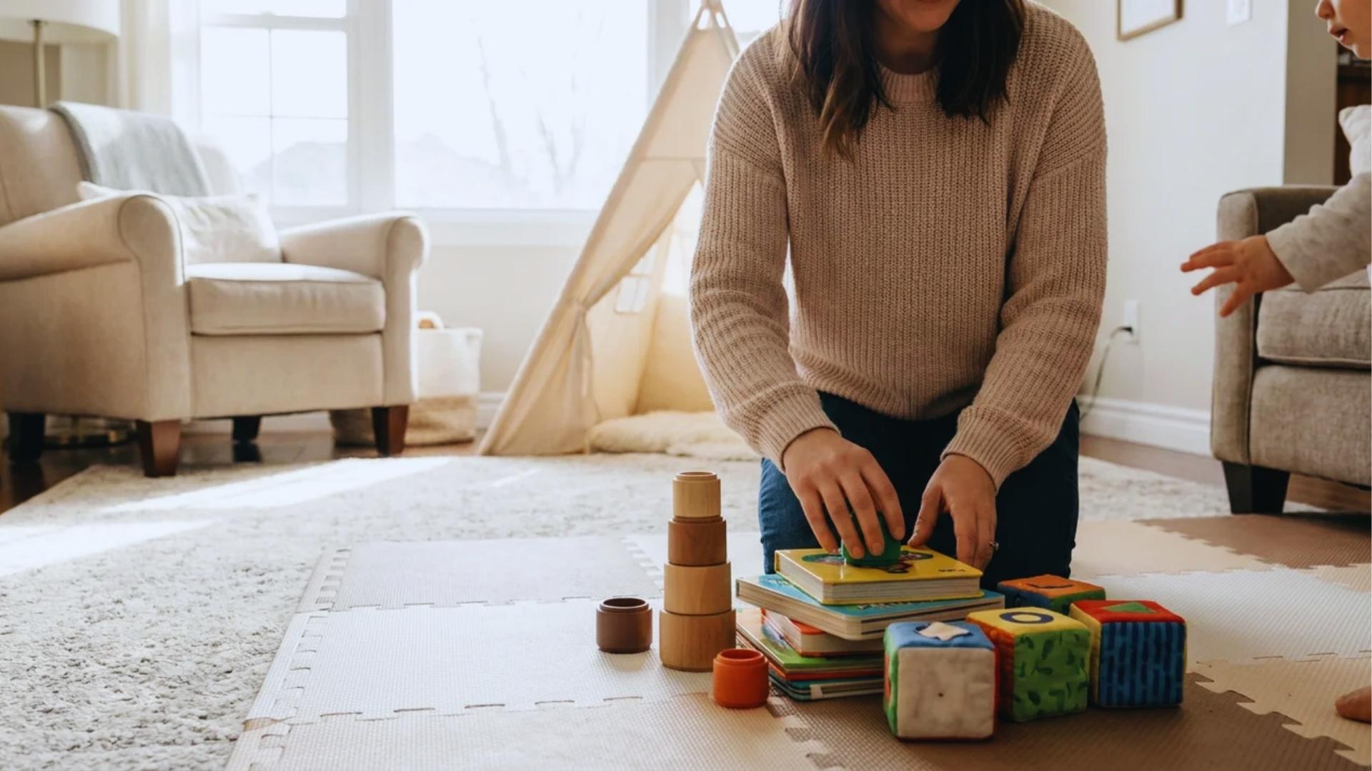 Parent preparing safe play area for curious one-year-old toddler.