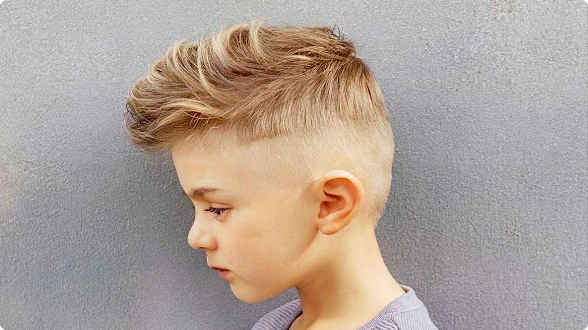 Toddler with side-swept undercut and combed top with faded sides, neat classic baby boy haircut.