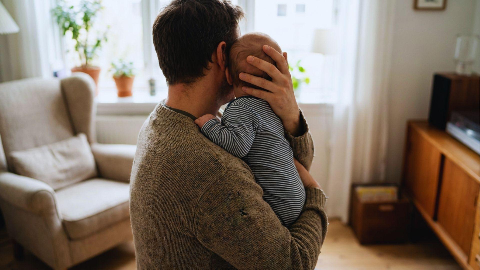 Parent burping baby comfortably in secure shoulder hold position.