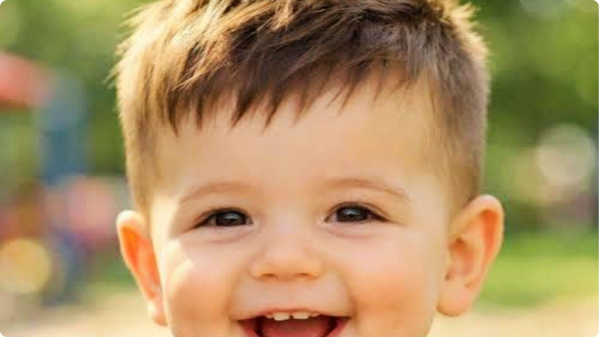 Smiling toddler with short textured crop and low fade, tousled bangs, cute outdoor baby boy haircut.
