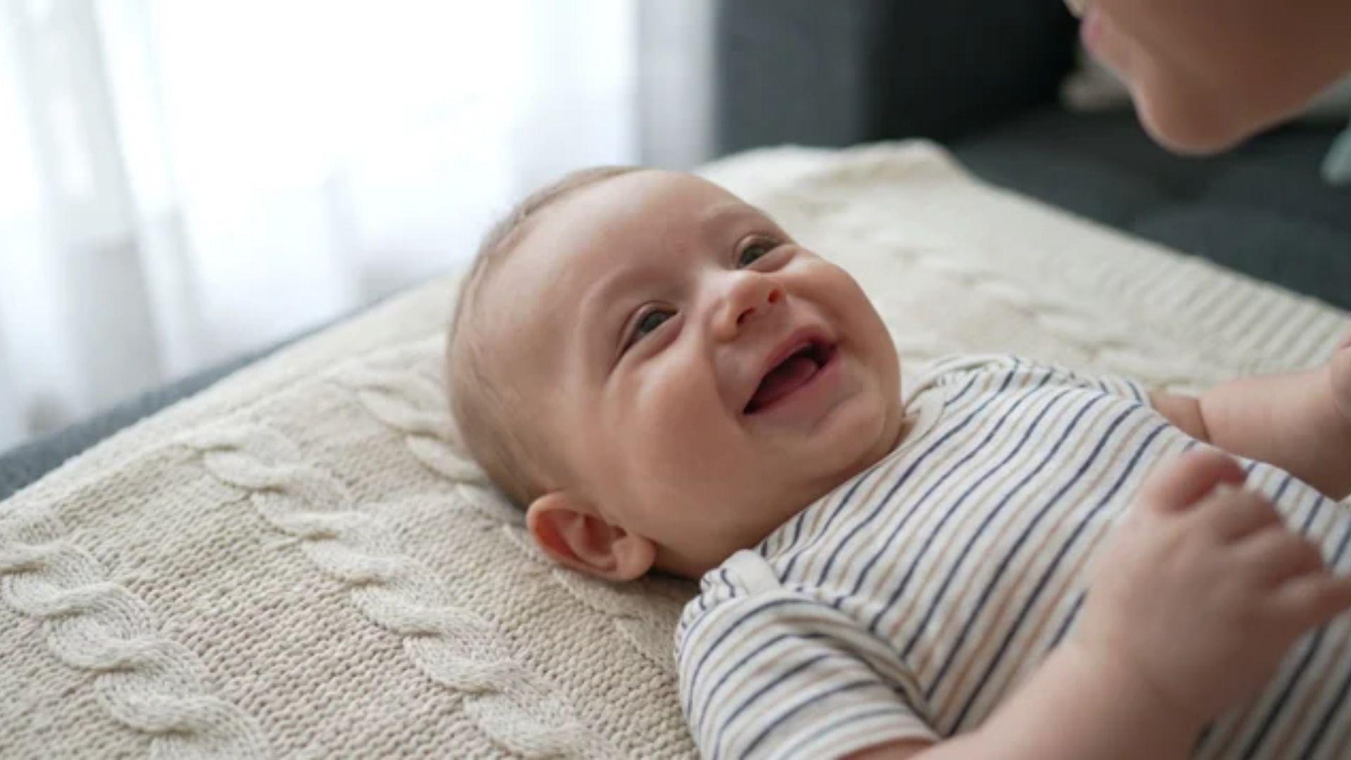 Infant looking toward a nearby face with a small social smile and slightly open mouth