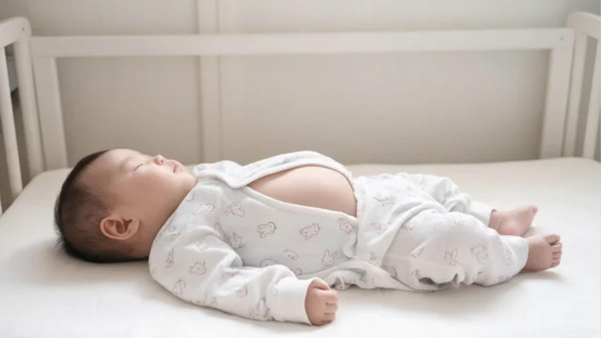 Sleeping infant lying on their back in a crib with the chest and abdomen visible