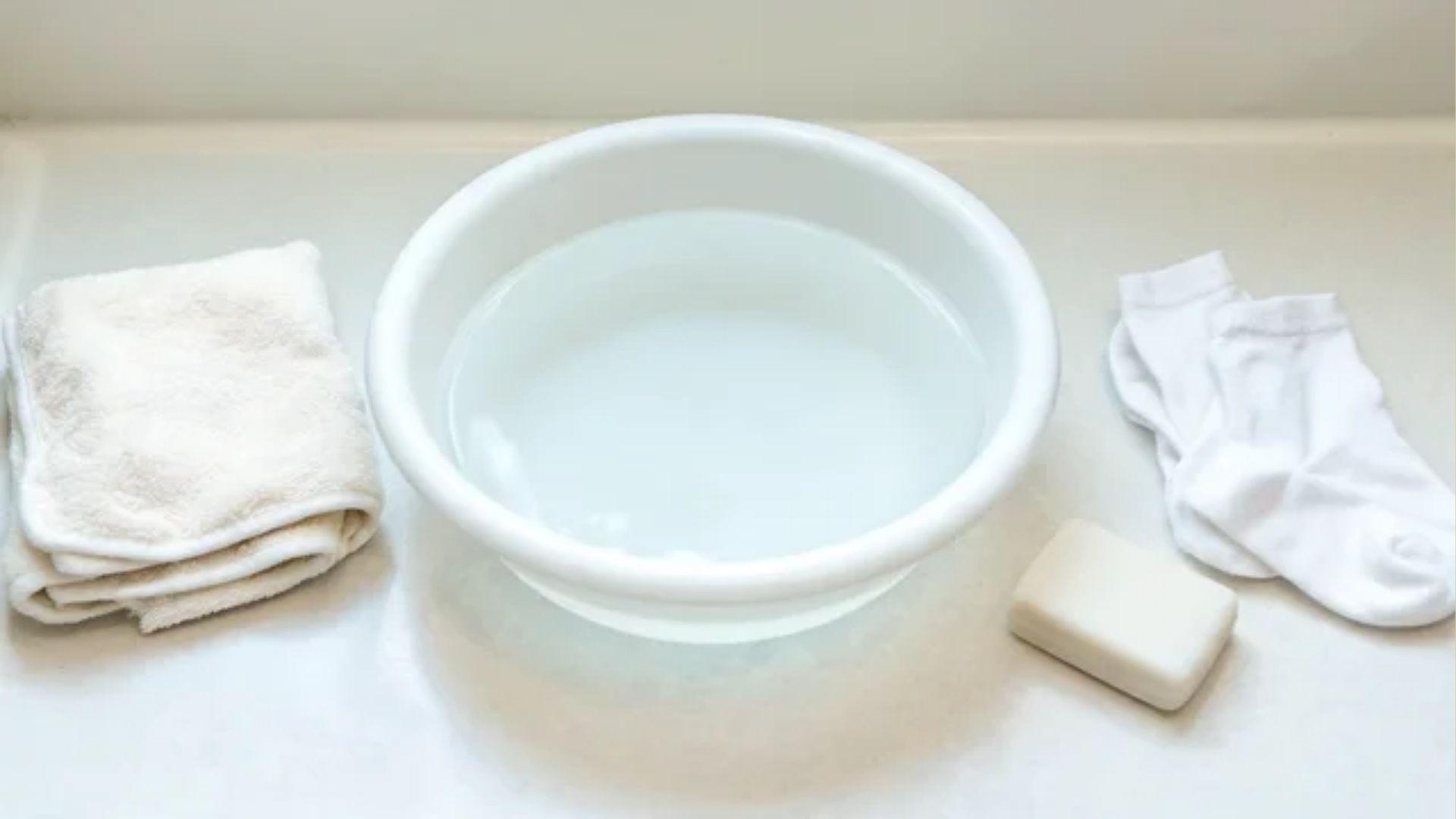Baby washcloth, basin of water, fragrance-free soap and clean cotton socks arranged for foot care