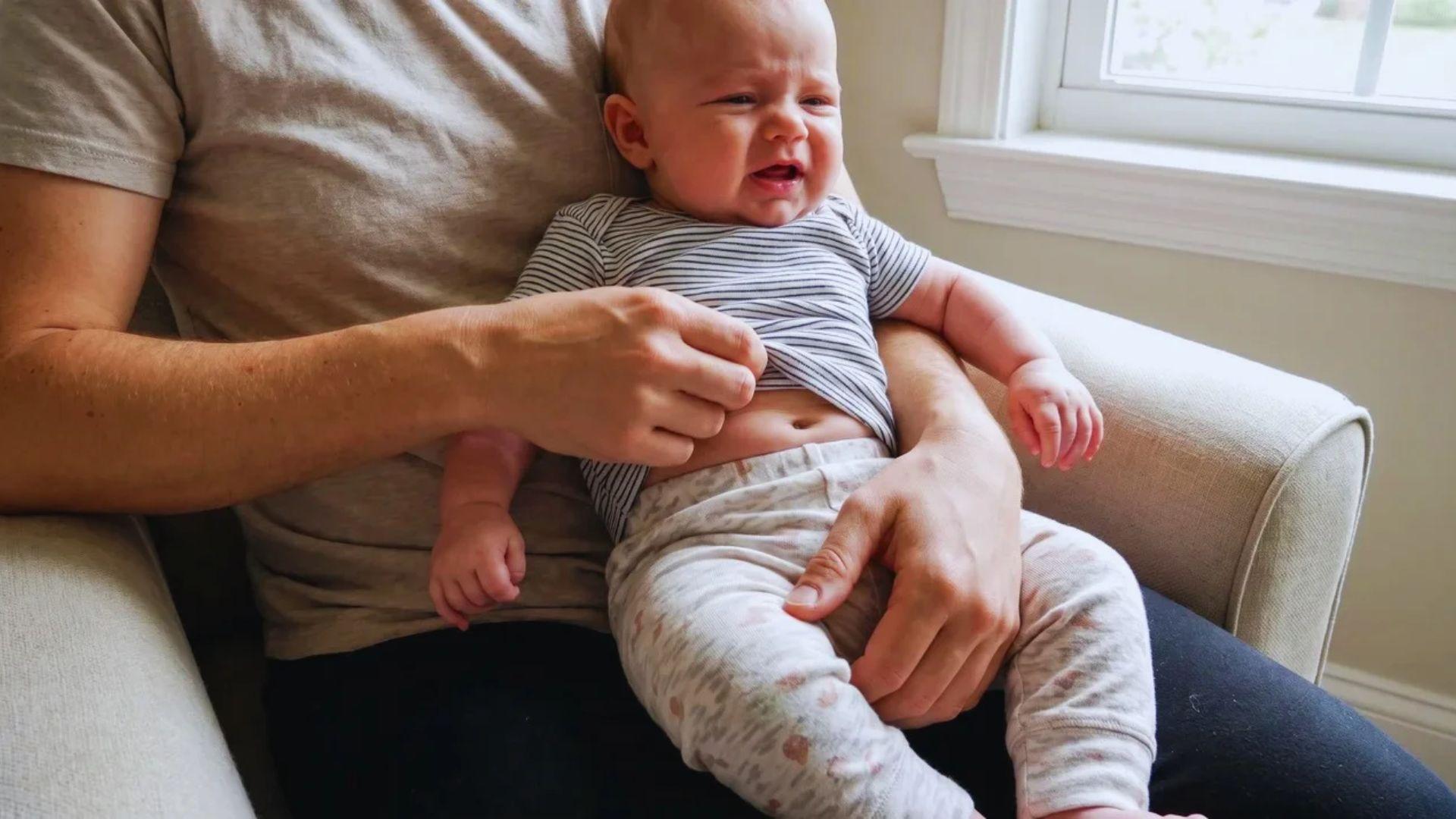 Parent holding a fussing baby while gently checking the waistband of the baby’s clothes.